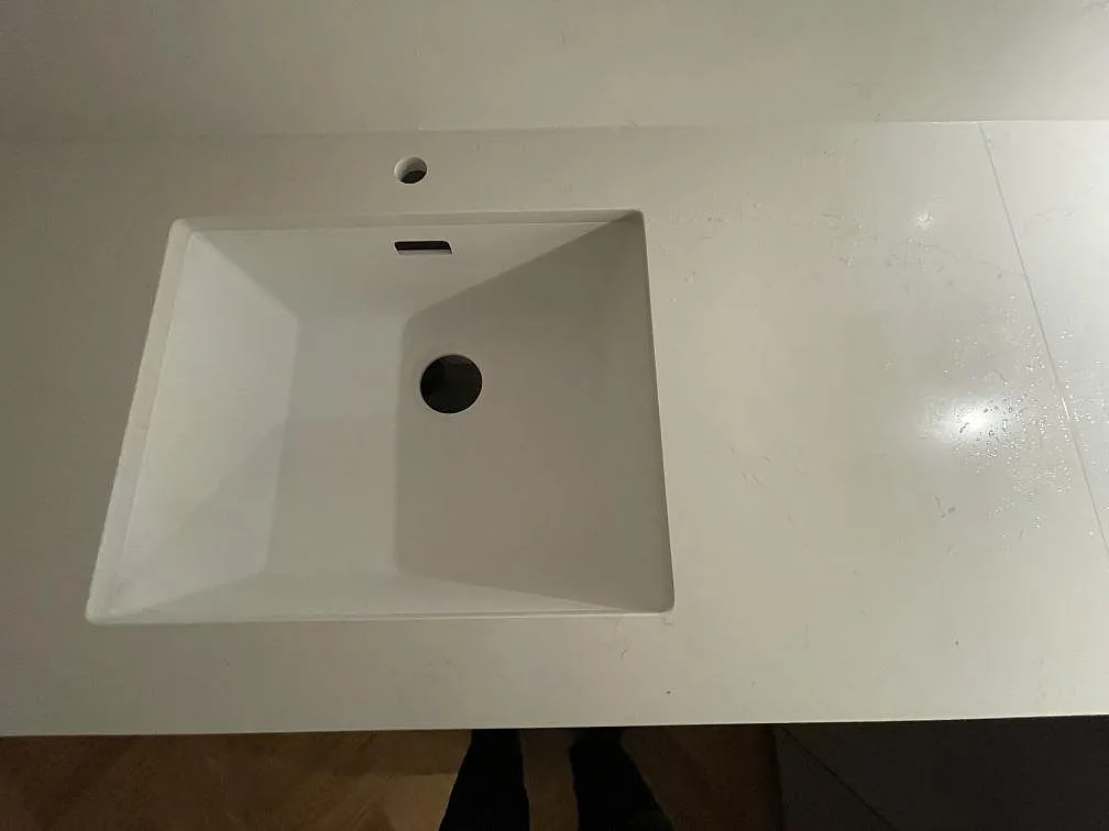 Underlimmad diskho i en polerad köksbänkskiva av vit Silestone Eternal Statuario med mjuka grå ådror, ovanifrån, i ett kök i Stockholm.