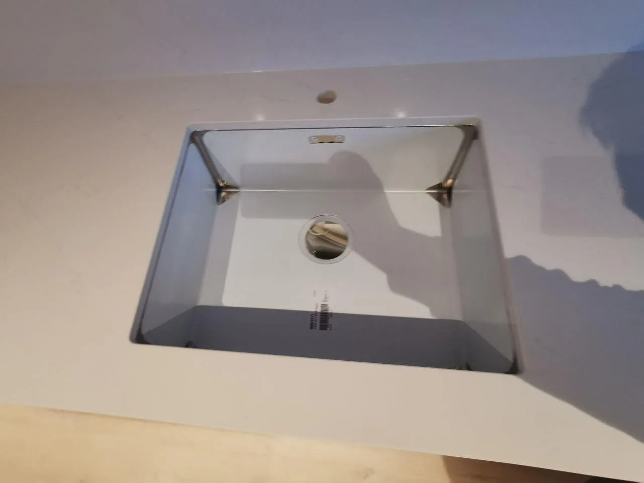 Underlimmad rostfri Blanco Claron-diskho monterad under polerad vit Silestone Eternal Statuario-bänkskiva i ett kök i Svedala.