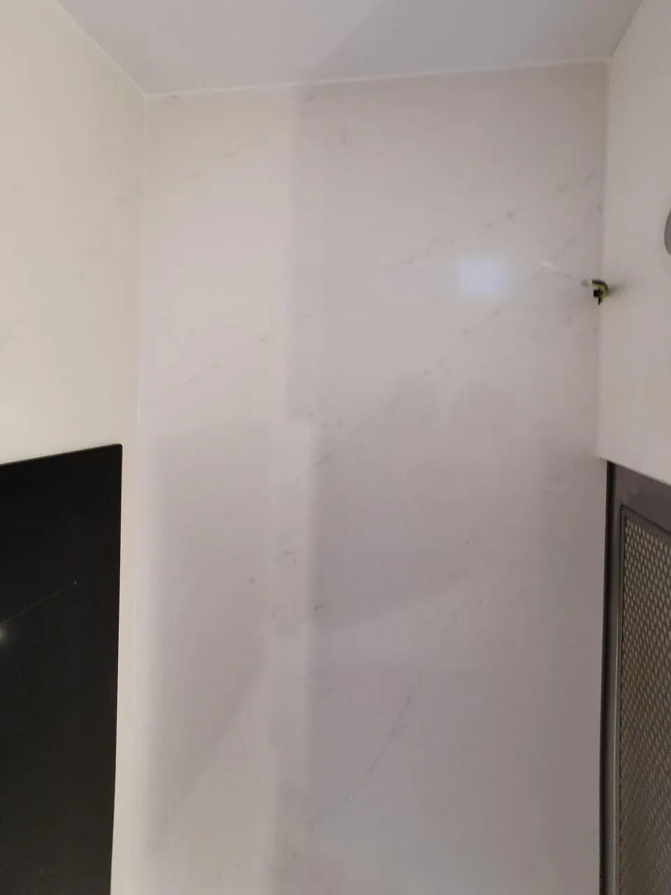 Uppvikt stänkskydd i polerad vit Silestone Eternal Statuario intill induktionshällen i ett kök i Svedala.