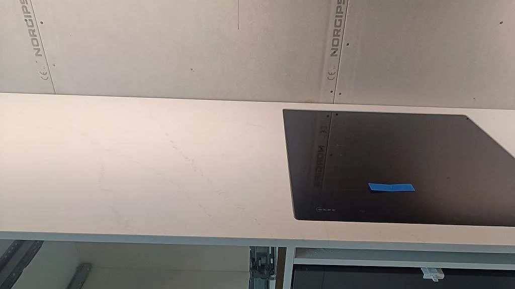 Detalj av polerad Silestone Eternal Statuario bänkskiva med induktionshäll och diskret grå ådring i Varberg.