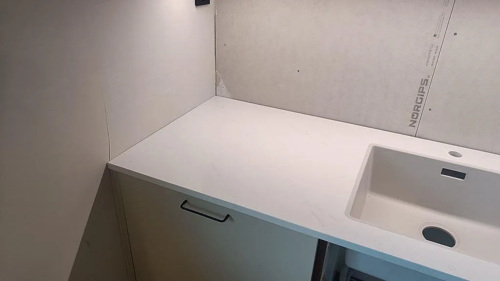 Bänkskiva i polerad Silestone Eternal Statuario med diskho och ljus väggskiva under montering i Varberg.