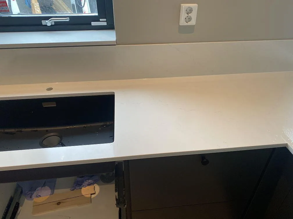 Bänkskiva i vit Silestone Eternal Statuario med underlimmad svart kompositdiskho och fönster i ett kök i Vellinge.