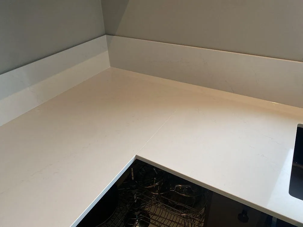 Hörnparti i polerad vit Silestone Eternal Statuario med stänkskydd i ett kök i Vellinge.