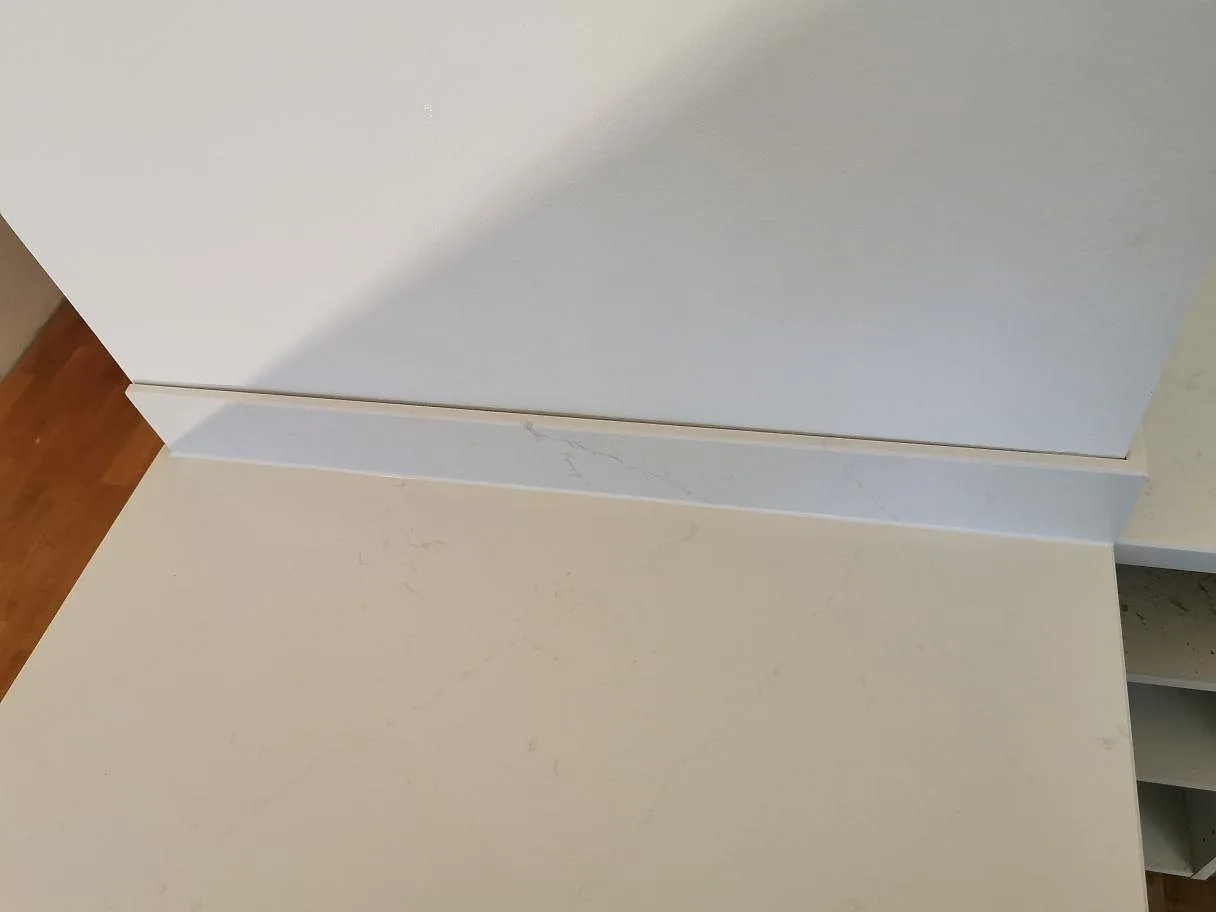 Närbild på polerad köksbänkskiva i vit Silestone Eternal Statuario med stänkkant och fin ådring i ett kök i Ystad.