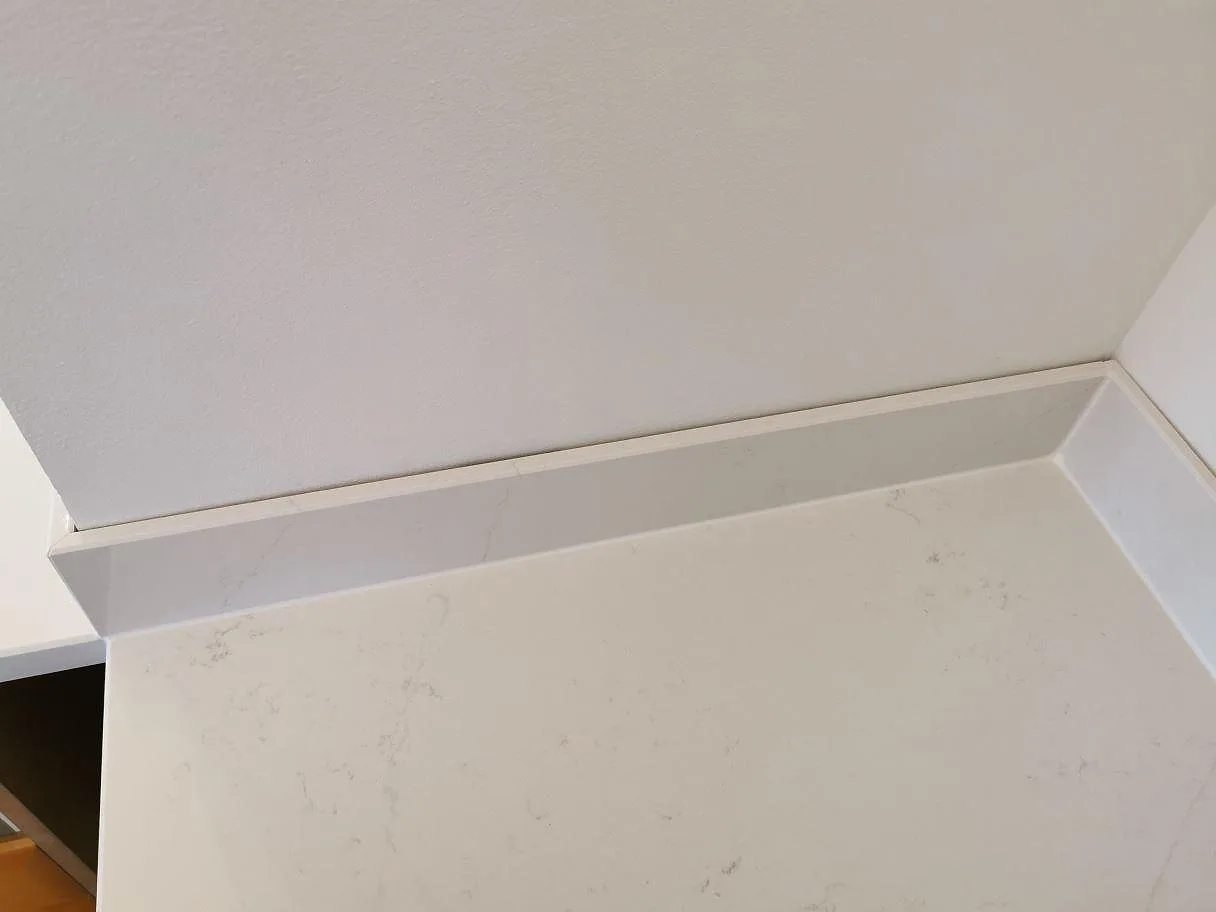 Köksbänkskiva i vit Silestone Eternal Statuario med uppvikt stänkskydd i samma sten i ett kök i Ystad.