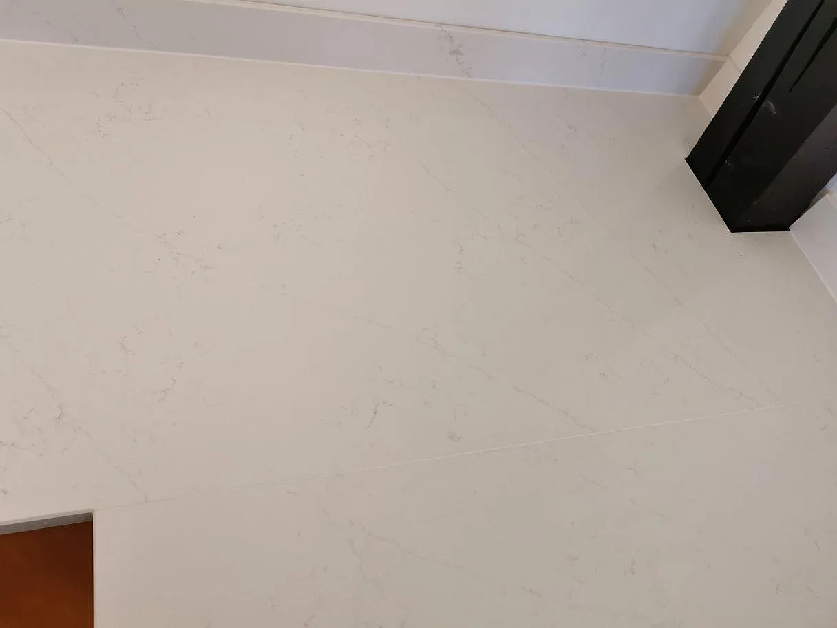 Polerad köksbänkskiva i vit Silestone Eternal Statuario med marmorlik ådring i ett kök i Ystad.