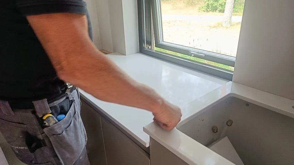 Polerad Silestone Eternal Statuario bänkskiva under montering vid fönstret, med synligt diskhourtag i ett kök i Ystad.