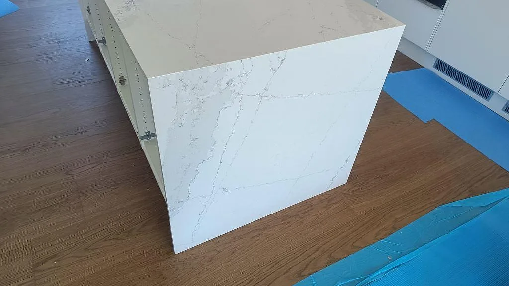 Närbild på vattenfallssida i Silestone Ethereal Dusk, vit polerad komposit med grå ådring på köksö i Halmstad.