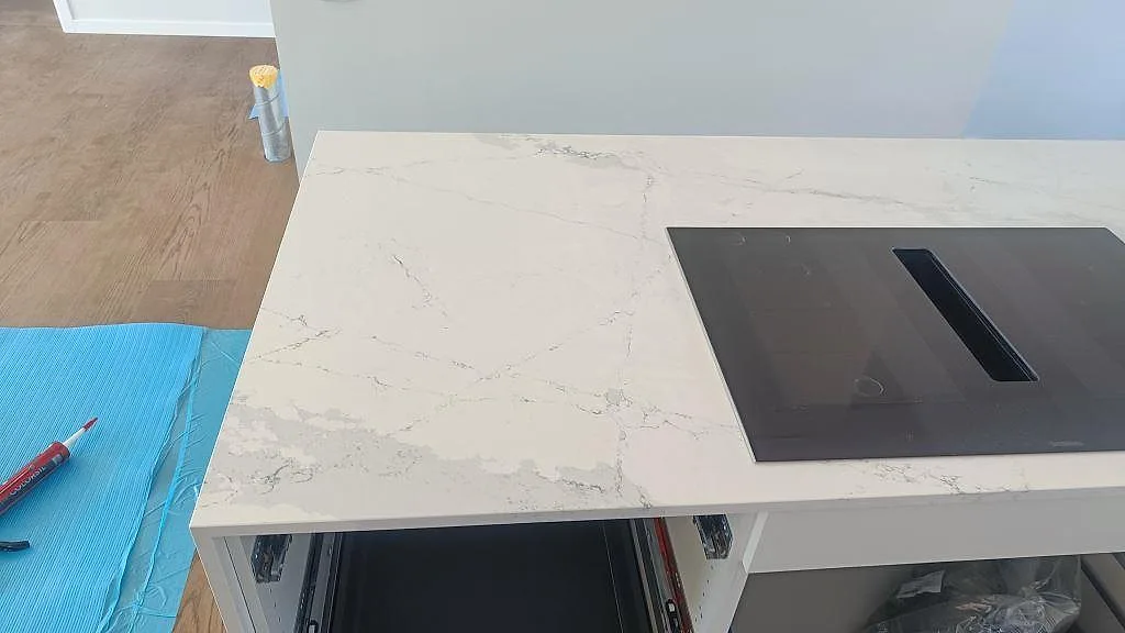 Svart induktionshäll infälld i polerad Silestone Ethereal Dusk köksbänkskiva med grå ådring i Halmstad.