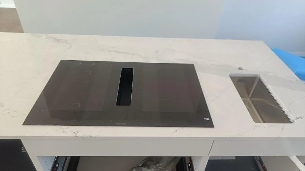 Polerad Silestone Ethereal Dusk bänkskiva med svart induktionshäll och rostfri diskho i ett ljust kök i Halmstad.