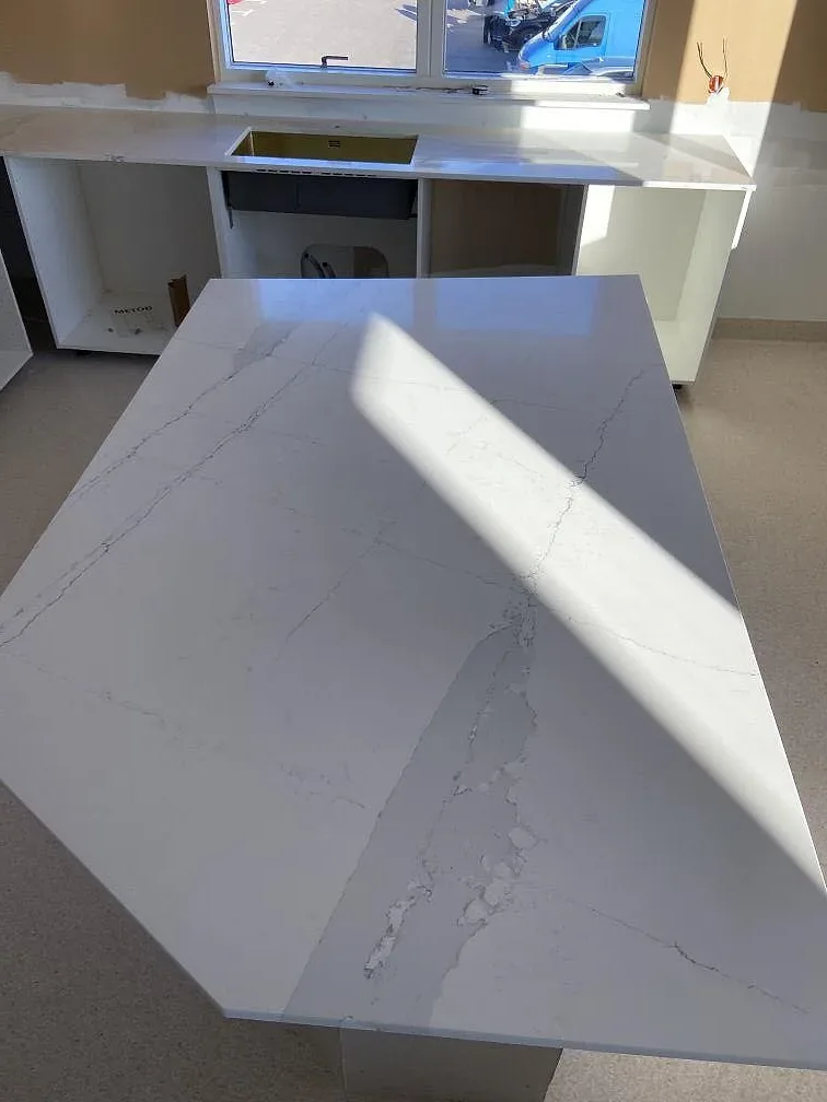 Vit Silestone Ethereal Dusk köksbänkskiva med mjuk grå ådring och solljus över ytan, monterad på köksö i ett kök under inredning i Oxie.