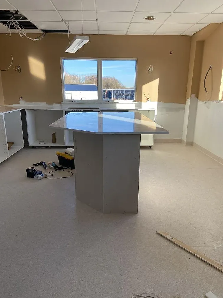 Köksö med vit Silestone Ethereal Dusk bänkskiva mitt i ett kök under inredning i Oxie, med fönster och kakelvägg i bakgrunden.