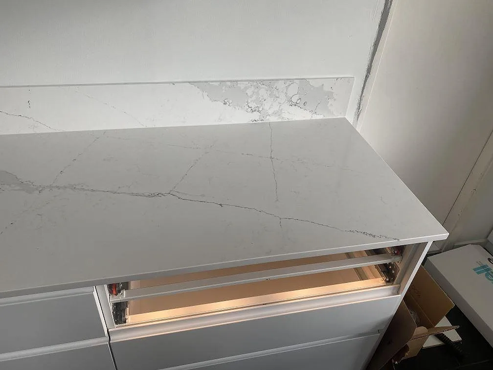 Bänkskiva i ljus Silestone Ethereal Dusk med högt stänkskydd i samma sten, polerad kvartskomposit med grå ådring, Staffanstorp.