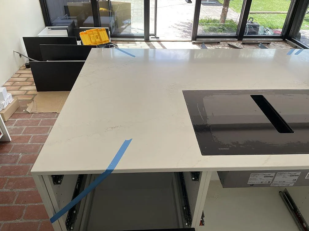 Stor köksö med polerad Silestone Ethereal Glow komposit, svarta hällen och glaspartier mot uteplatsen i Falsterbo.