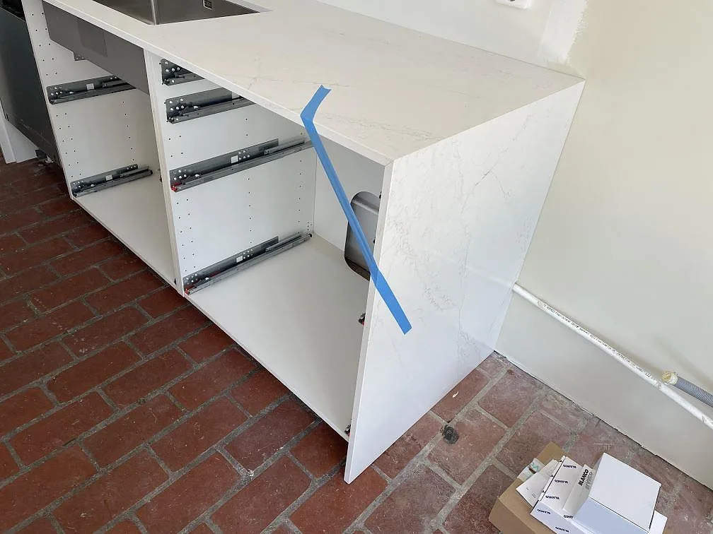Sidovy av köksö med vit polerad Silestone Ethereal Glow komposit och tegelgolv i Falsterbo.