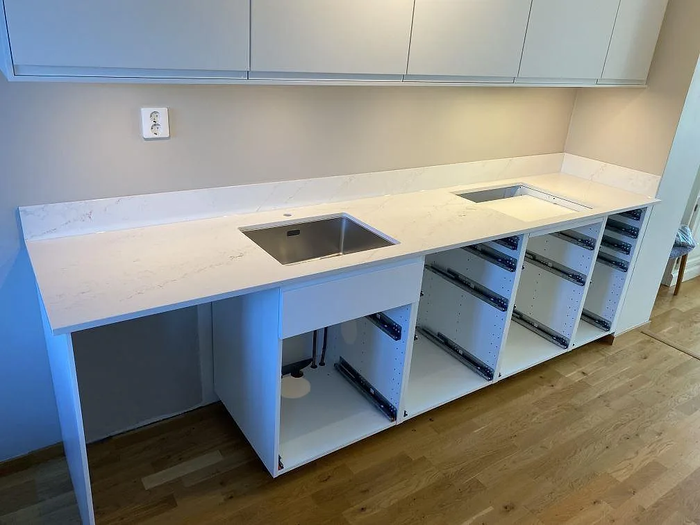 Köksbänkskiva i polerad Silestone Ethereal Glow komposit med låg stänkkant, rostfri diskho och hällöppning i ett kök i Halmstad.