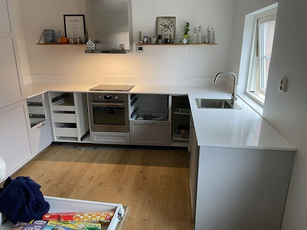 Köksbänkskiva i varmvit Silestone Ethereal Glow, polerad, med övermonterad rostfri diskho och infälld induktionshäll i ett L-format kök i Lund.