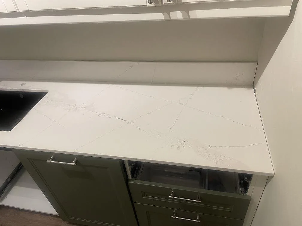 Närbild på polerad Silestone Ethereal Haze köksbänkskiva med grå ådring, svart diskho i kanten och låg stänkkant i Helsingborg.