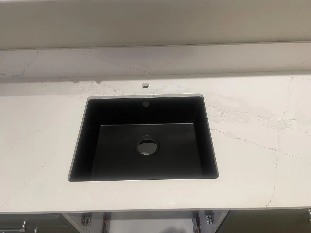 Svart diskho och blandarhål i en polerad Silestone Ethereal Haze köksbänkskiva med låg stänkkant i Helsingborg.
