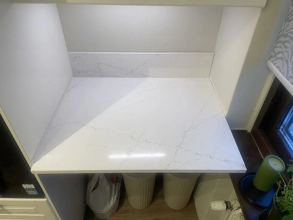 Polerad Silestone Ethereal Haze bänkskiva med ljus ådring och uppvikt stänkkant på sidoytan i ett kök i Helsingborg.