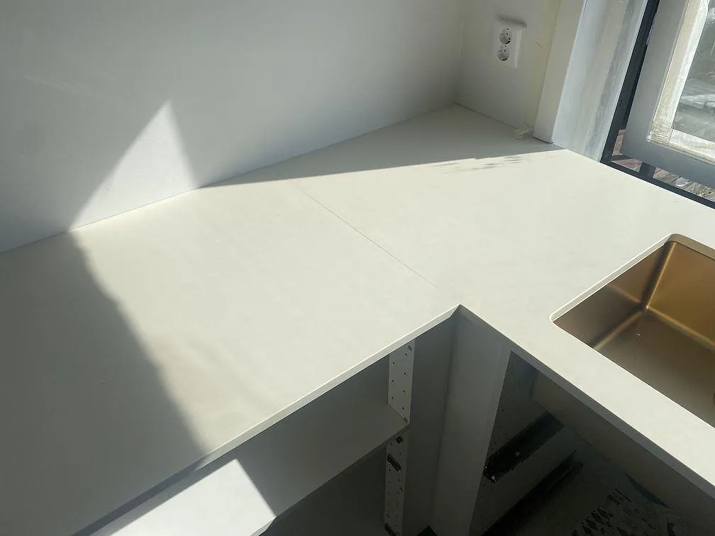 Hörnskarv på bänkskiva i matt vit Silestone Faro White i Malmö, med underlimmad diskho i kopparton.