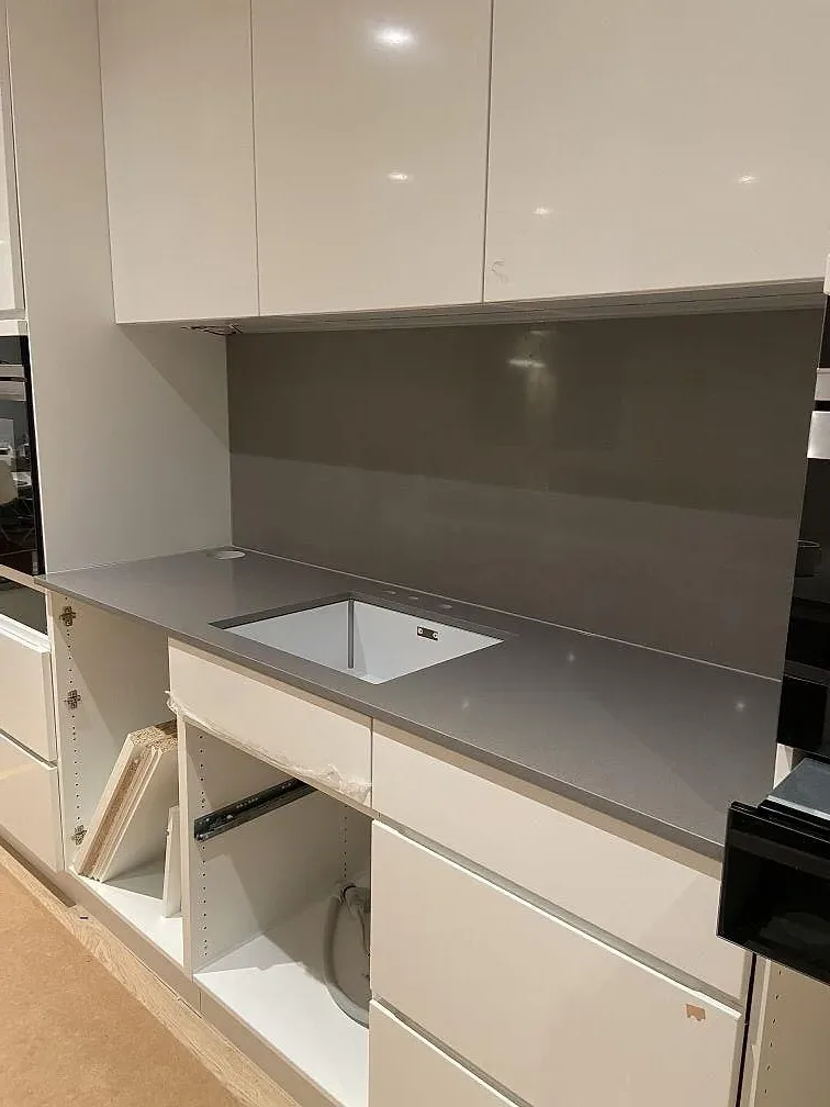 Polerad grå Silestone Gris Expo köksbänkskiva monterad på vita köksstommar under installation i Mölnlycke.