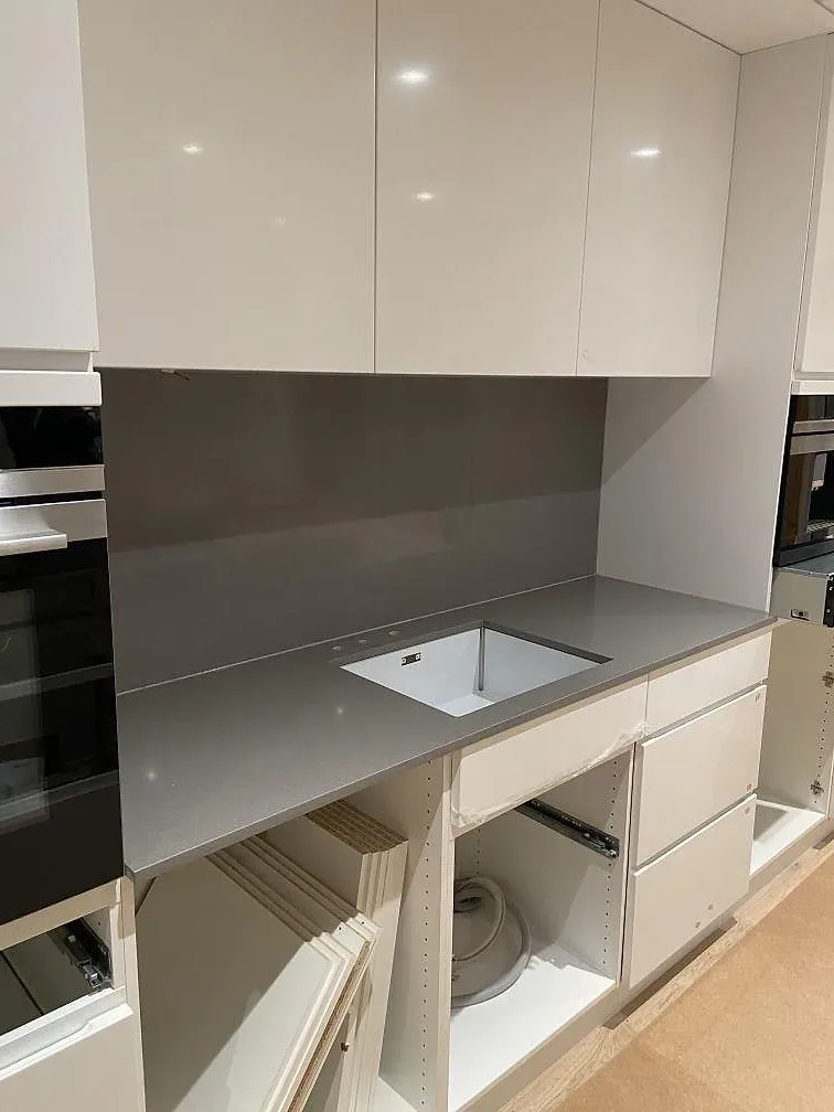 Grå Silestone Gris Expo köksbänkskiva i L-form med urtag för underlimmad rostfri diskho på vita stommar i ett kök i Mölnlycke.