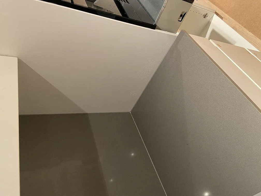 Närbild på polerad grå Silestone Gris Expo köksbänkskiva med uppvikt stänkskydd och blandarehål i ett kök i Mölnlycke.