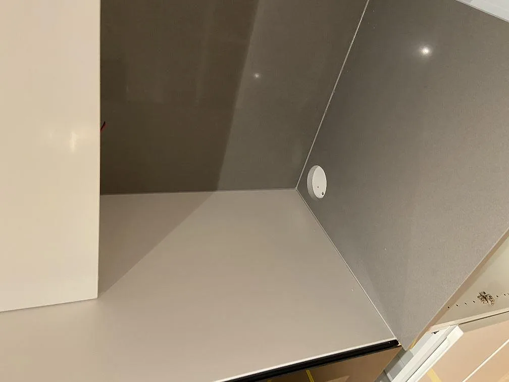 Hörnparti av grå Silestone Gris Expo köksbänkskiva med matchande stänkkant och blandarehål i ett kök i Mölnlycke.