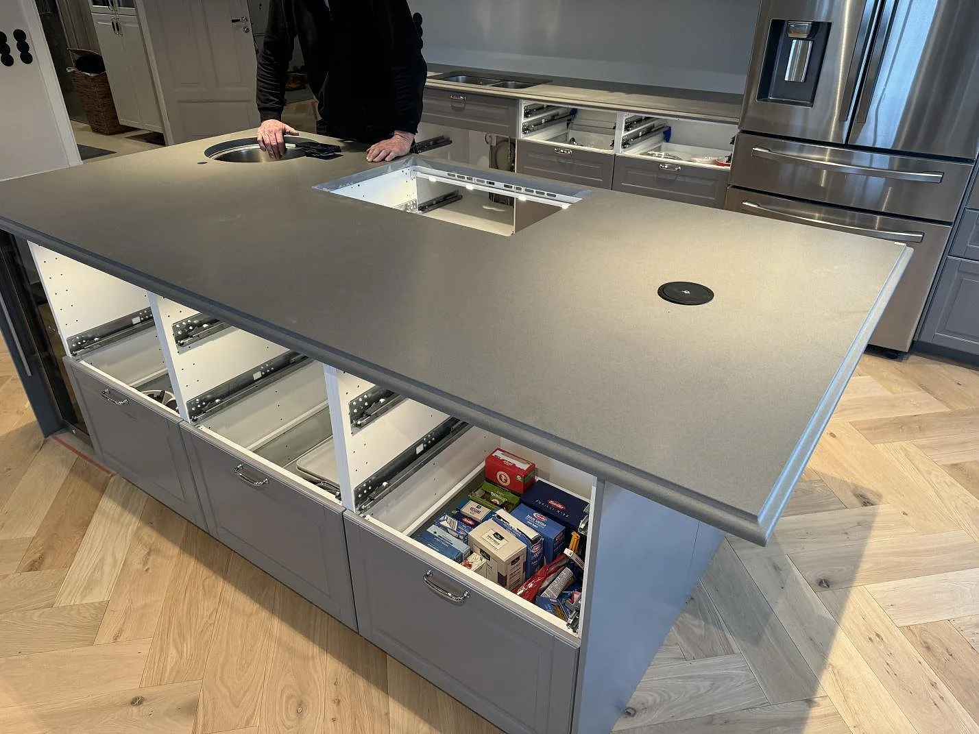 Stor köksö i grå Silestone Gris Expo, 30 mm Mocka, med rund prep-ho, hälluttag och väggbänk i ett kök i Sölvesborg.