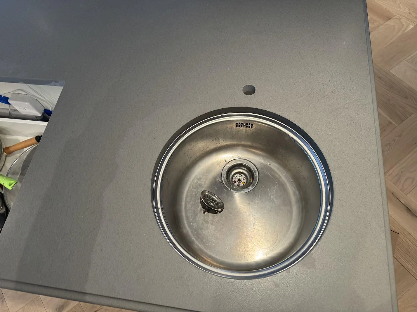 Detalj av rund rostfri prep-ho i köksö av Silestone Gris Expo, med matt Mocka-yta och grå ton i Sölvesborg.