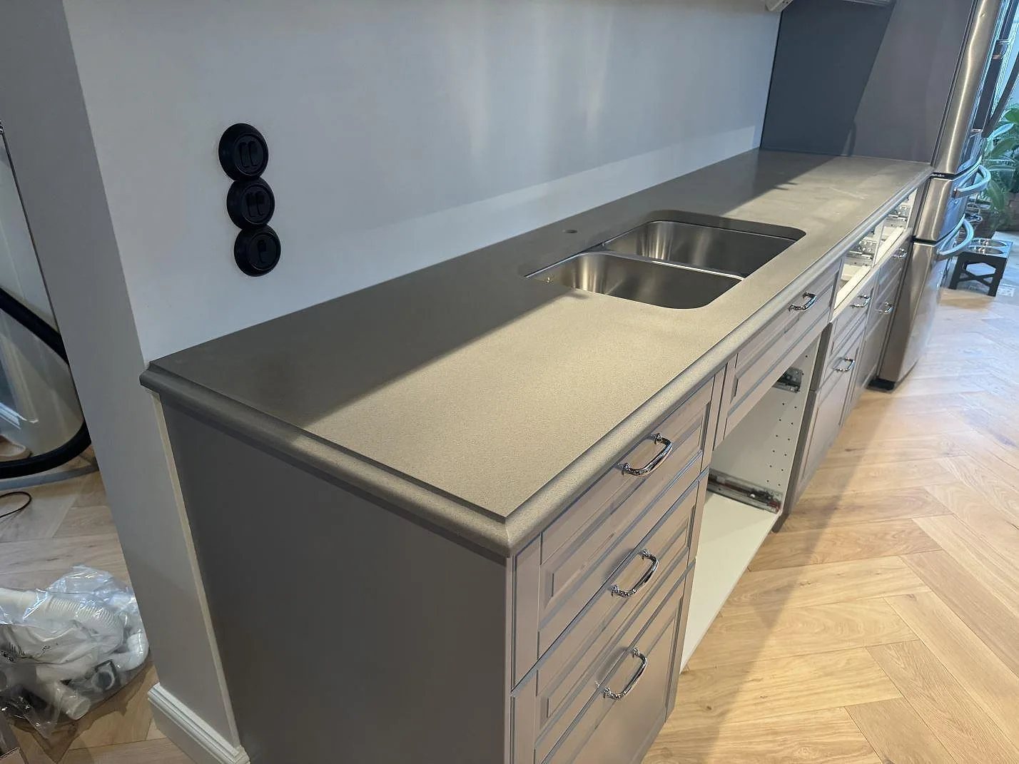 Köksbänkskiva längs väggen i Silestone Gris Expo, 30 mm Mocka, med rostfri dubbelho och uppvikt stänkkant i Sölvesborg.