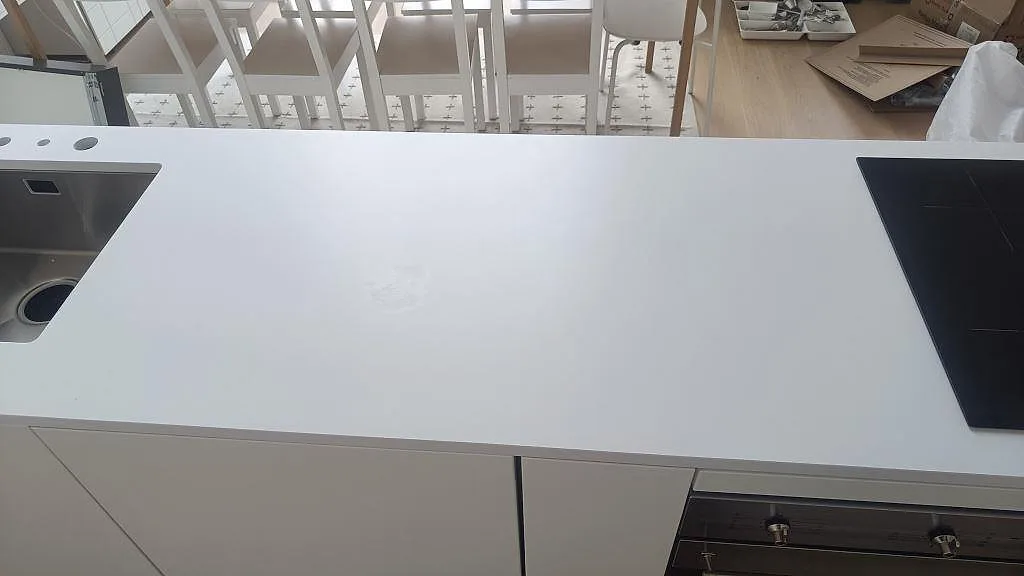 Ovansida av köksö i Silestone Iconic White, matt Mocka, med rostfri diskho och induktionshäll i ett kök i Ystad.