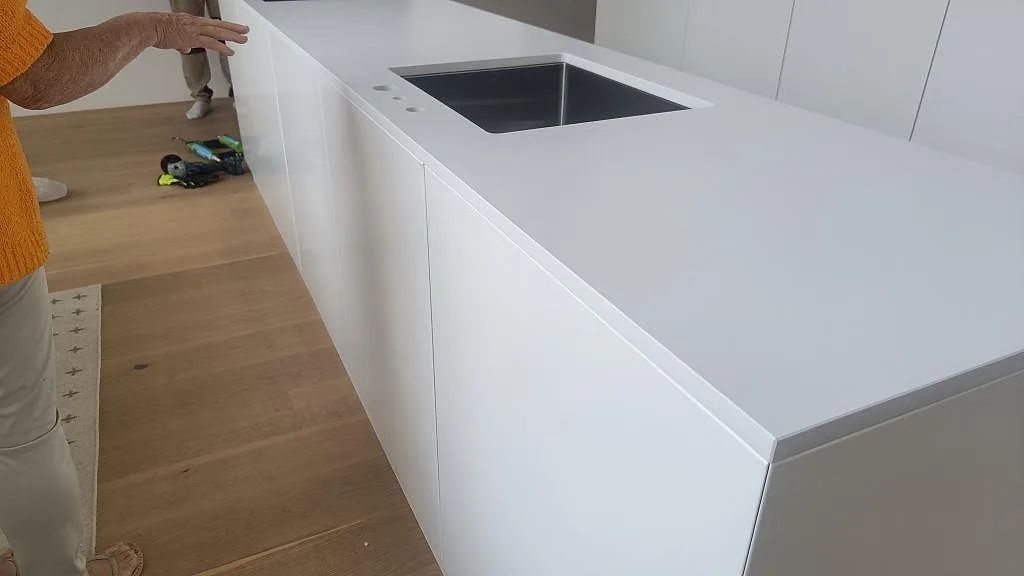 Sidovy av köksö med bänkskiva i Silestone Iconic White, matt Mocka, och underlimmad rostfri diskho i Ystad.