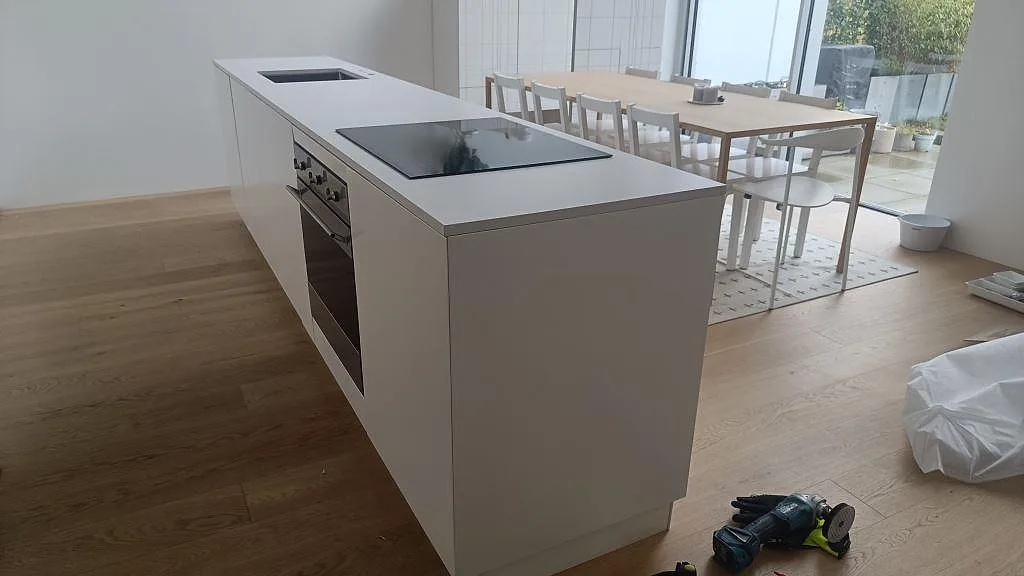 Stor köksö med bänkskiva i vit Silestone Iconic White, matt Mocka, med induktionshäll och underlimmad diskho i Ystad.