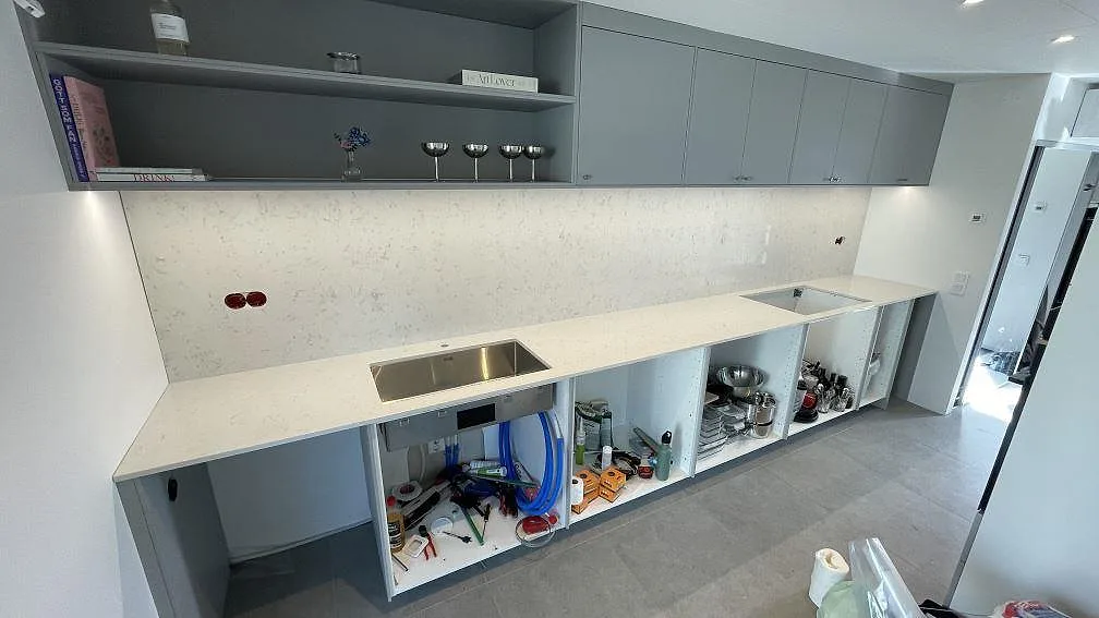 Köksbänkskiva i polerad Silestone Lagoon, ljus kvartskomposit, med hög väggbeklädnad och rostfri diskho i Billdal.