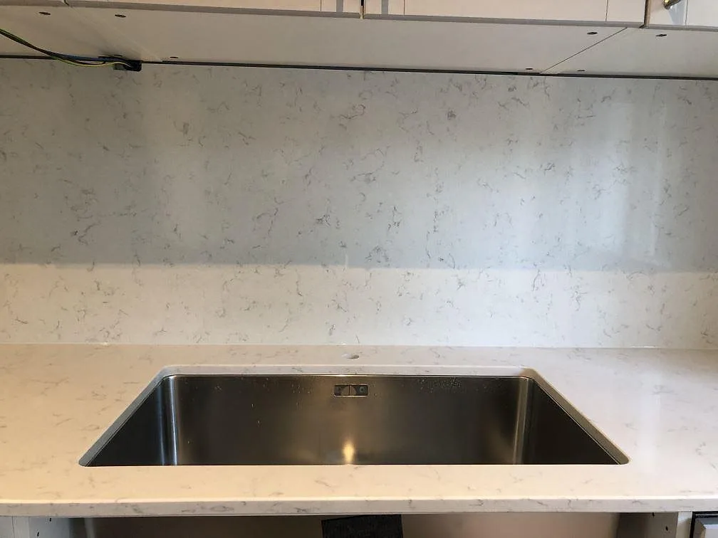 Underlimmad rostfri diskho i en polerad köksbänkskiva av Silestone Lagoon med stänkskydd i Falsterbo.
