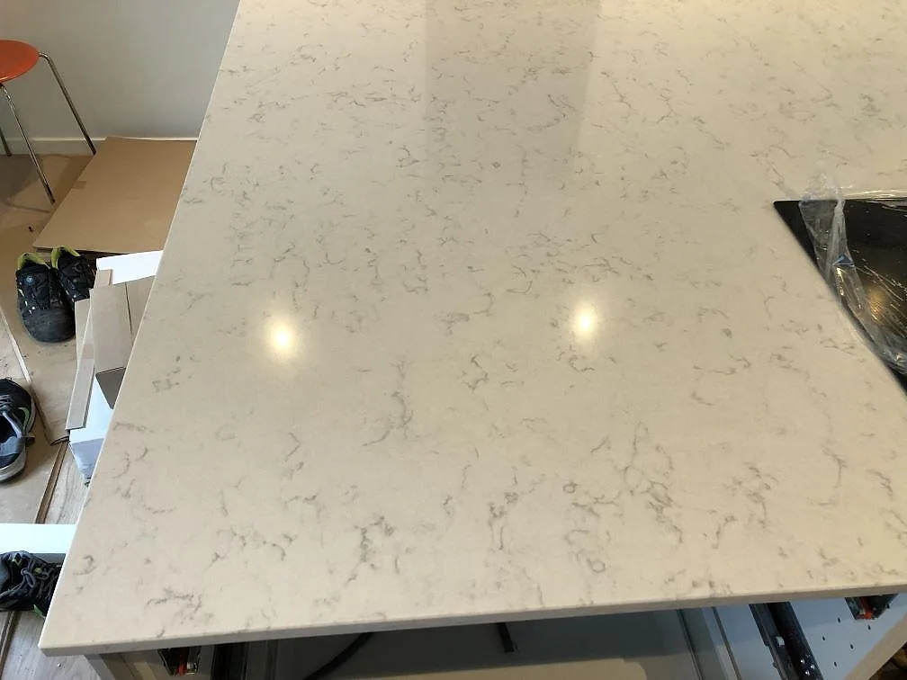 Top-down på polerad köksö i Silestone Lagoon med mjuk grå ådring i ett kök under montering i Falsterbo.