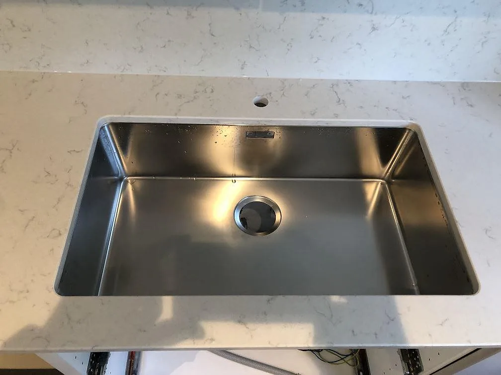 Detalj av underlimmad rostfri diskho i polerad Silestone Lagoon bänkskiva i ett kök i Falsterbo.