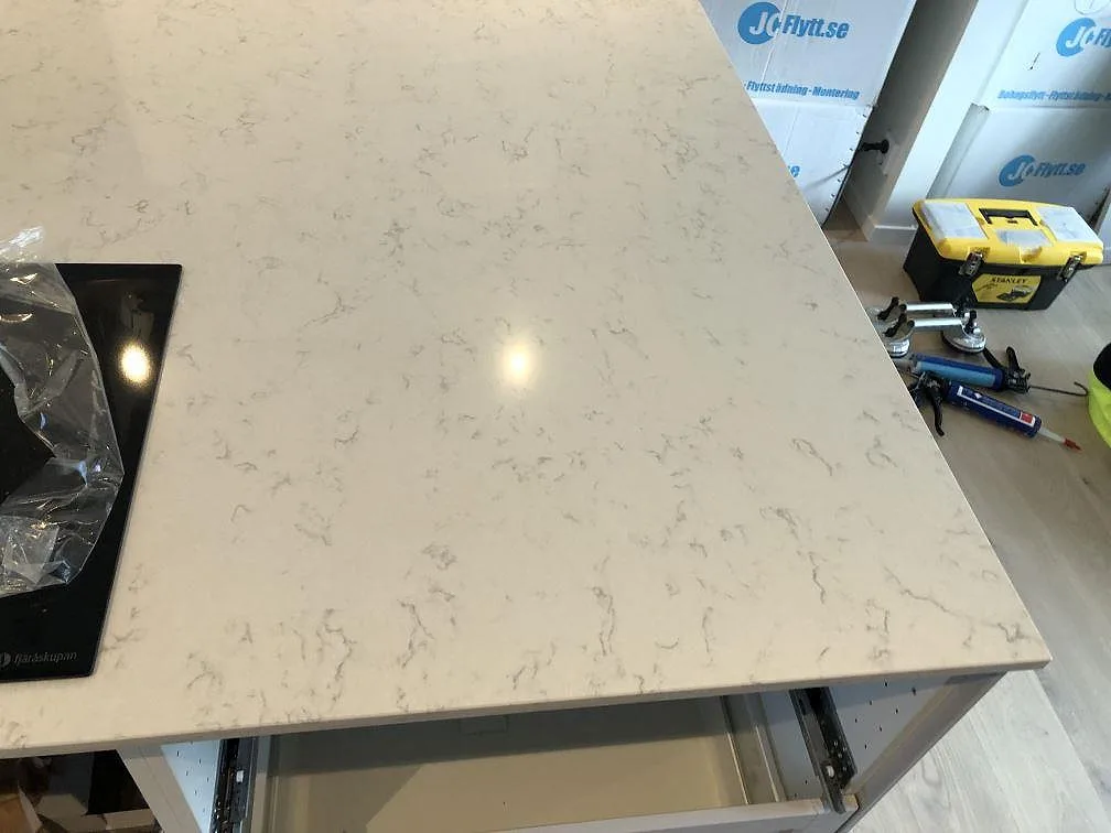 Köksö i polerad Silestone Lagoon med spishällsurtag och rak fasad kant i ett kök i Falsterbo.