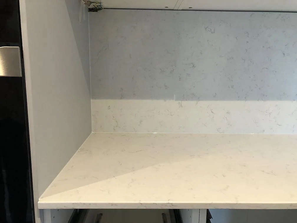 Bänkskiva och stänkskydd i polerad vit Silestone Lagoon med diskret grå ådring i ett kök i Falsterbo.