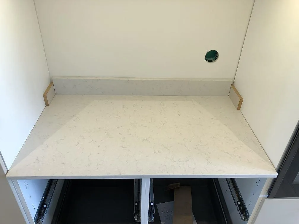 Köksbänk i creme Silestone Lagoon med uppvikt stänkkant mot vägg i ett kök i Fjälkinge.