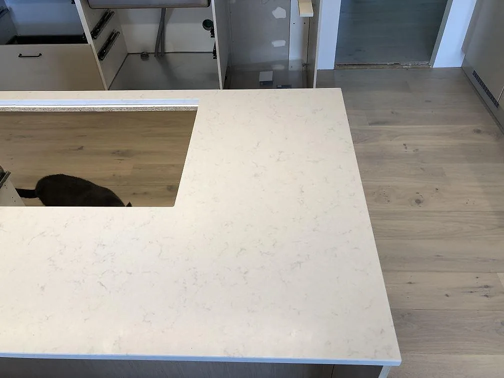 Hörn av köksö i creme Silestone Lagoon med hällurtag och fin grå ådring i ett kök i Fjälkinge.