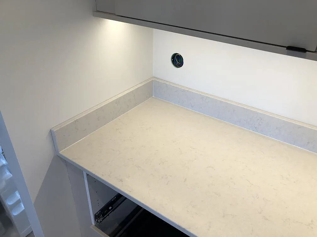 Returbänk i matt creme Silestone Lagoon med uppvikt stänkkant under montering i ett kök i Fjälkinge.