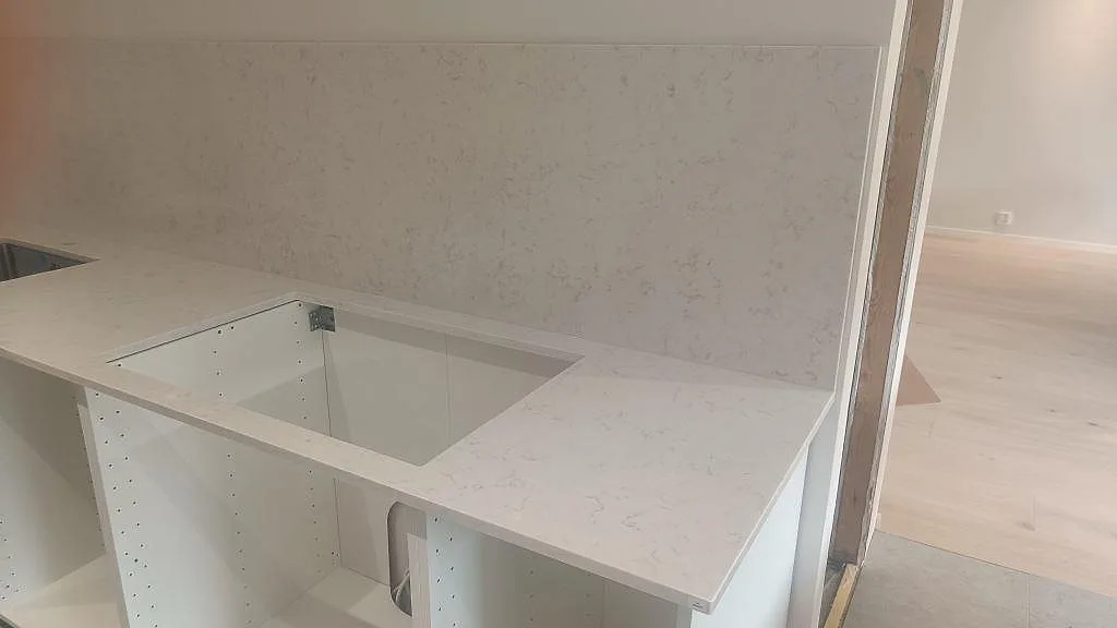 Köksbänkskiva i polerad Silestone Lagoon med matchande stänkskydd och utskärning vid väggbänken i Höllviken.
