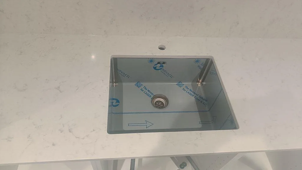 Polerad Silestone Lagoon med underlimmad diskho, blandarhål och ljust stänkskydd i köket i Höllviken.