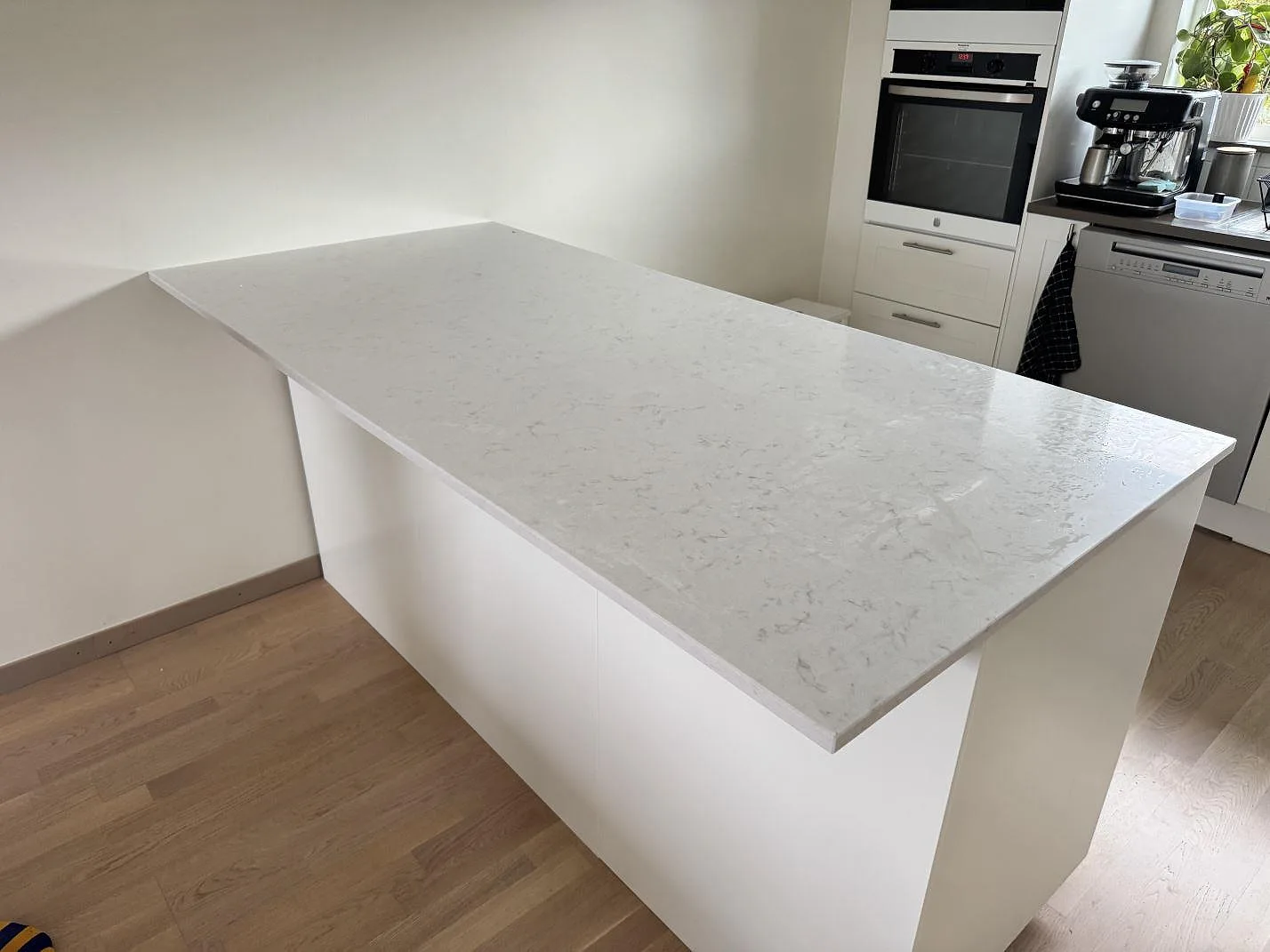Köksö med köksbänkskiva i polerad Silestone Lagoon, ljus kvartskomposit med grå ådring, i ett kök i Limhamn.