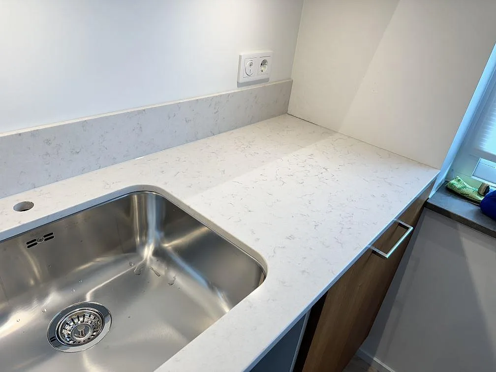 Närbild av polerad Silestone Lagoon som köksbänkskiva med rostfri underlimmad diskho och stänkskydd i Lomma.