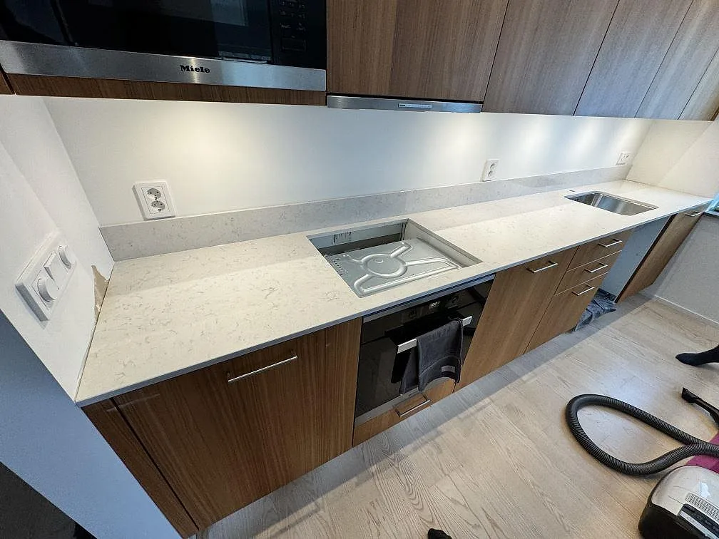 Köksbänkskiva i vit Silestone Lagoon, polerad, med stänkskydd, rostfri diskho och öppning för häll i ett kök i Lomma.