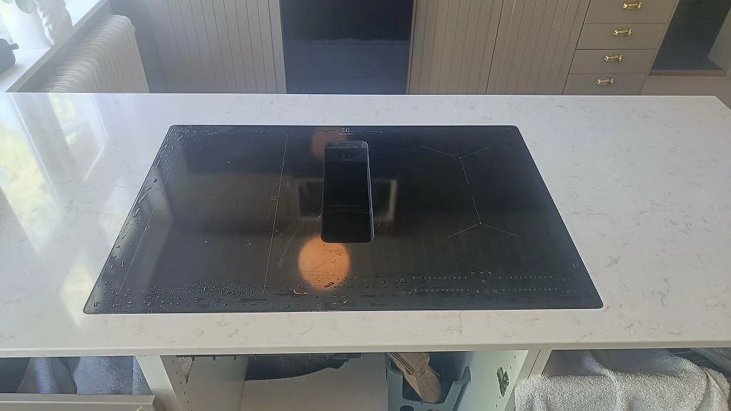 Svart häll monterad i polerad Silestone Lagoon, 20 mm, på köksö med pärlspontad inredning i Mariestad.